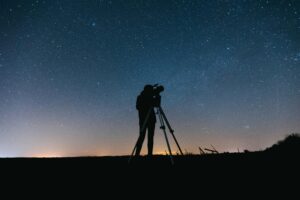 Silhouette of a person using a telescope under a starry night sky, perfect for astronomy themes.